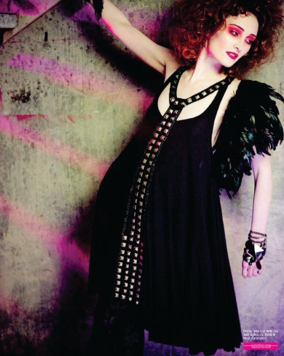 Woman laid on concrete wearing black dress with pink vibrant eye make-up