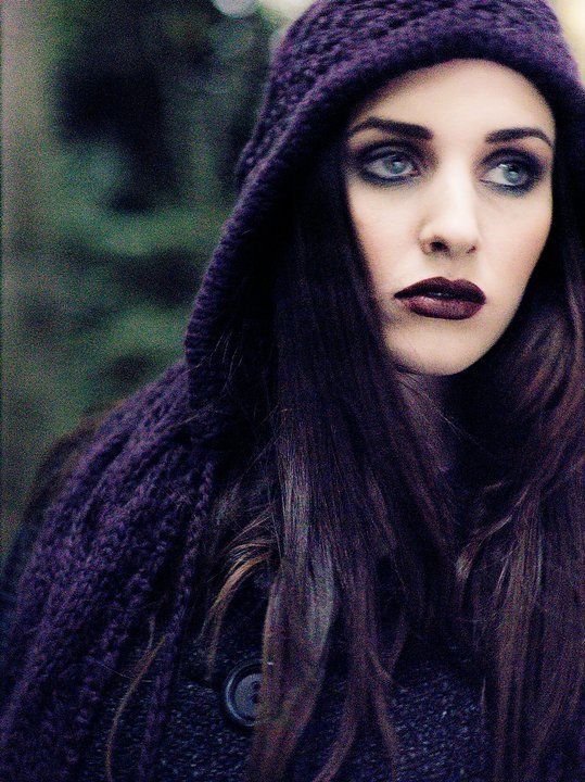 Woman with dark make-up and purple hoodie looking sullen