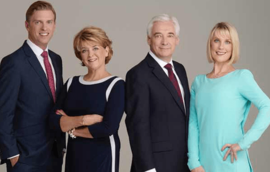 Row of 4 official looking individuals smiling and wearing suits