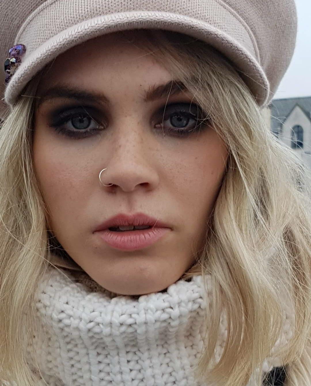 Close-up of woman looking at camera wearing pink beret with dark smoky eyes