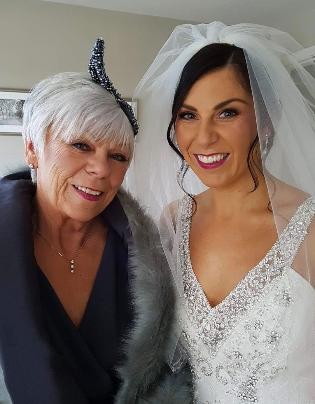 2 women smiling at camera, dressed for a wedding