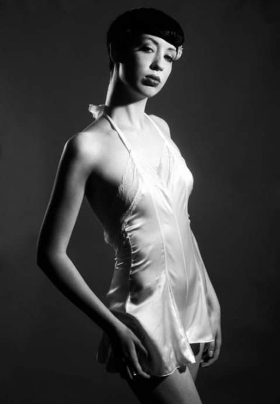 Black and white image of woman posing wearing tight silky dress