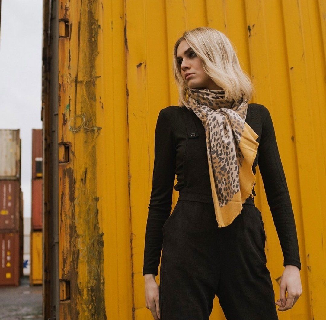Woman stood proud in suit, looking away from camera with yellow container behind her