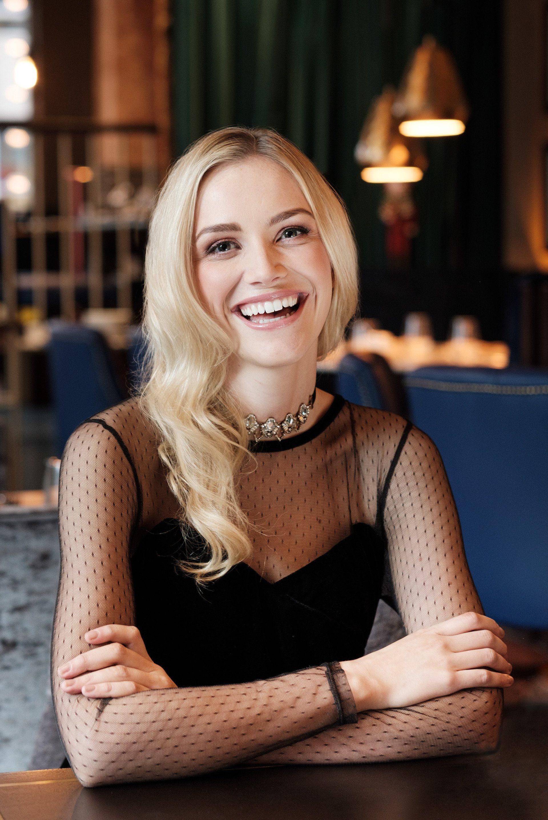 Woman sat at table laughing, looking directly at camera
