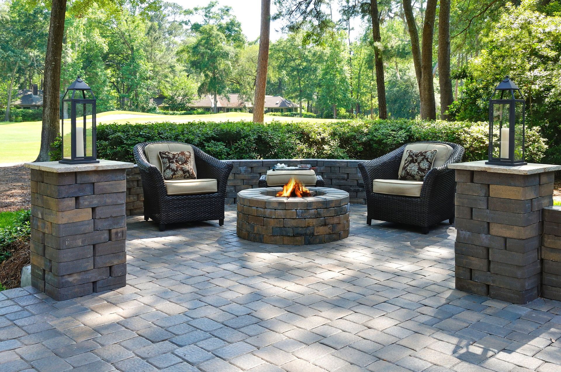 Outdoor fire hearths with cozy chairs on pavers in lush garden setting for relaxing evenings. 