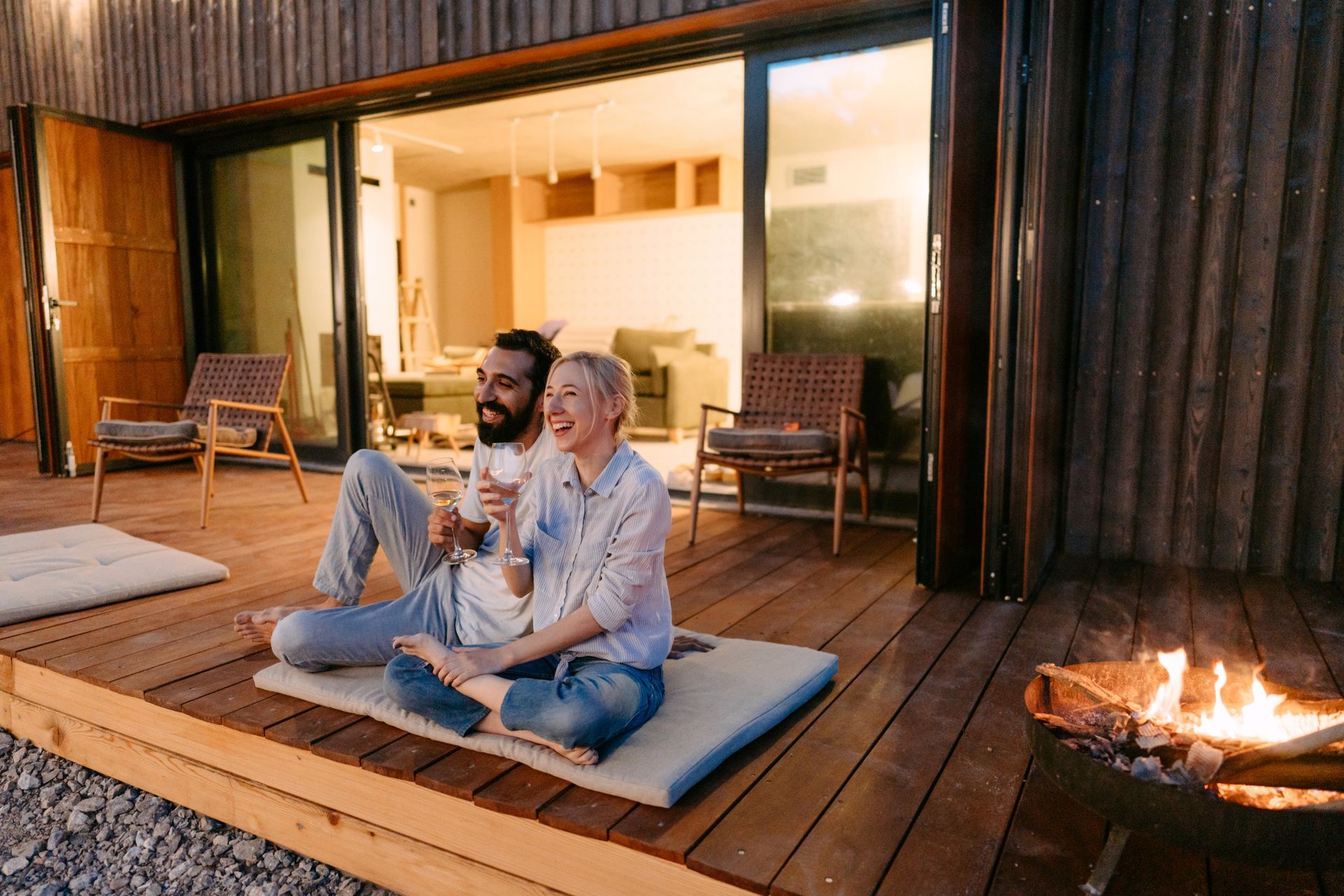 Young couple drinking wine by the fire pit. 