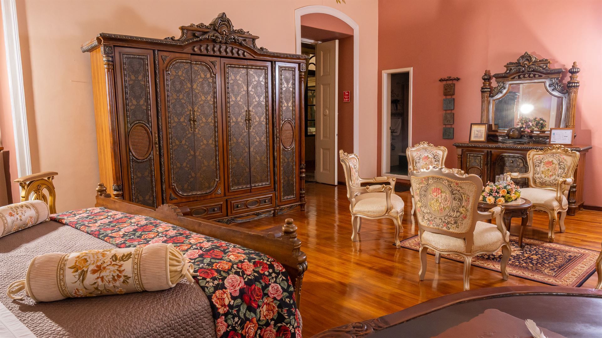 A bedroom with a bed , chairs , dresser and mirror.