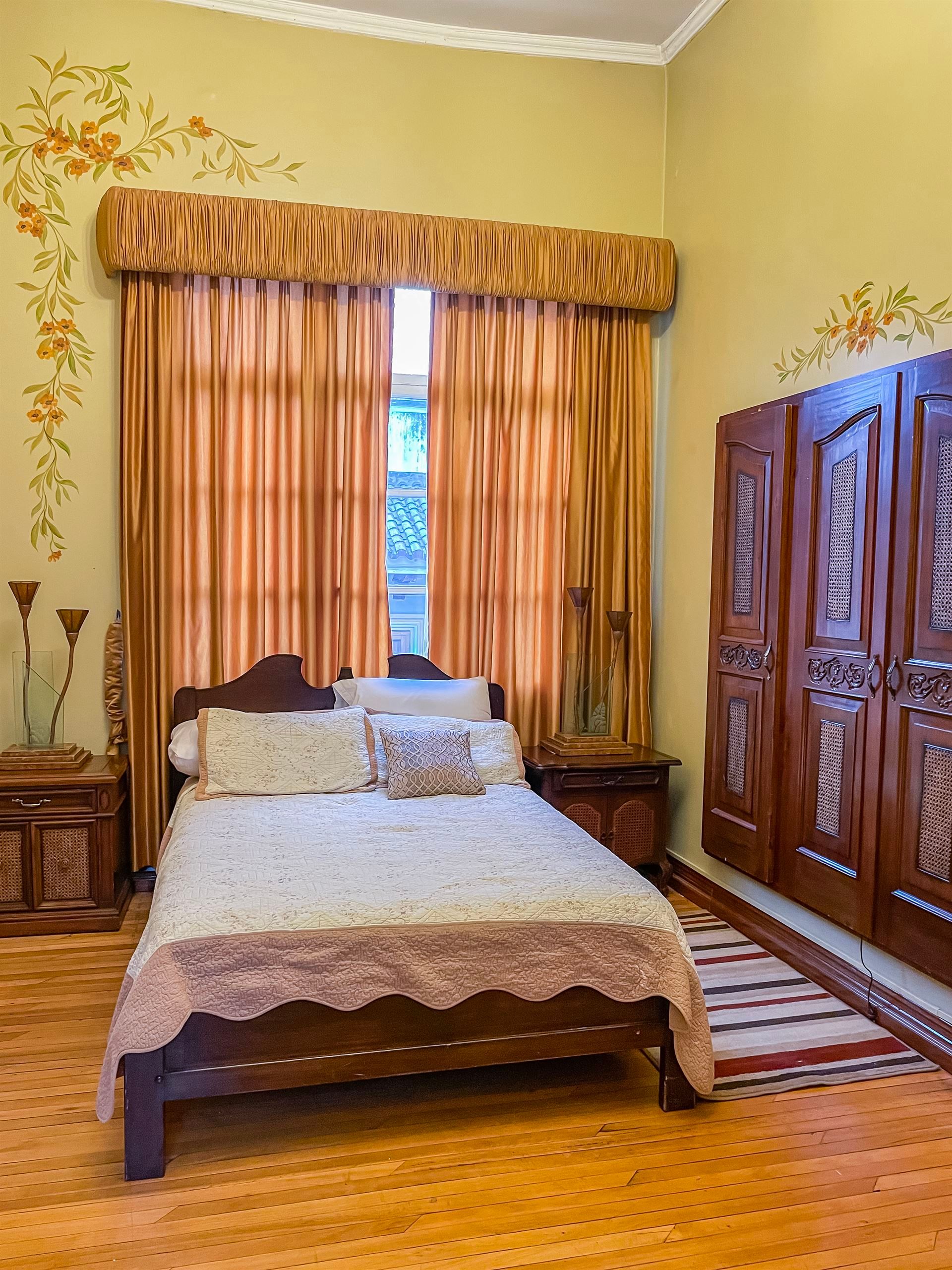 A bedroom with a bed , nightstands , curtains and a window.