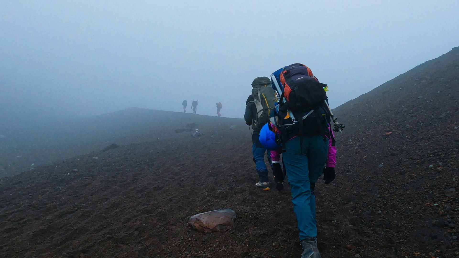 A group of people are hiking up a hill in the fog.