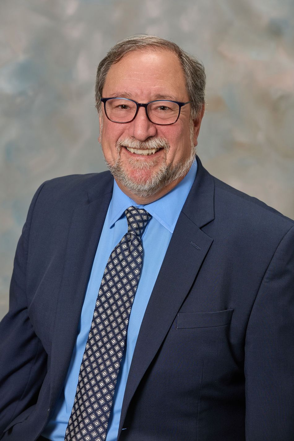 A man in a suit and tie is smiling for the camera