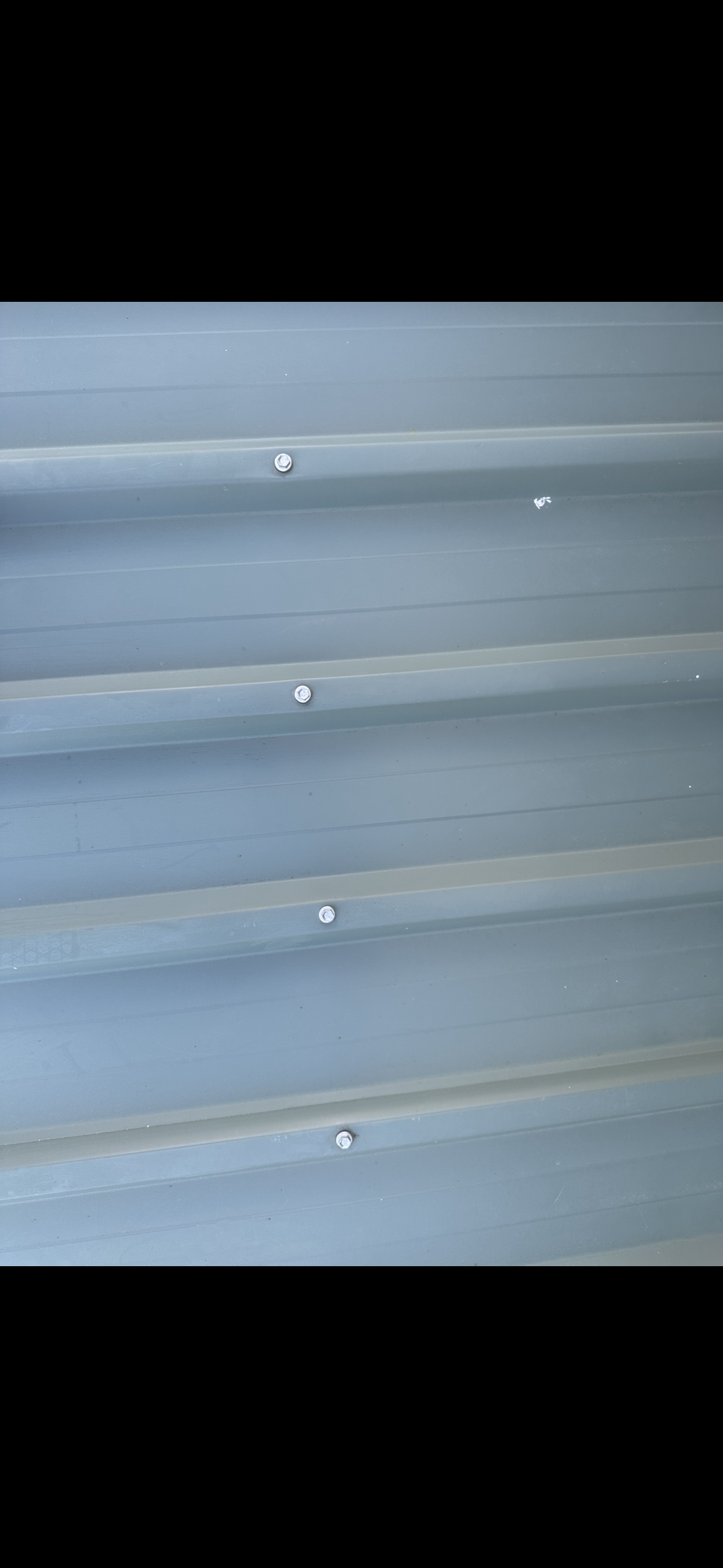 Close-up of Gray Corrugated Metal Siding With Several White Fasteners — Whirly Bird King in Redcliffe, QLD