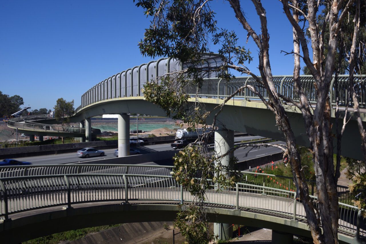A Bridge Over a River With Trees in the Foreground and a Highway in the Background — Whirly Bird King in Strathpine, QLD