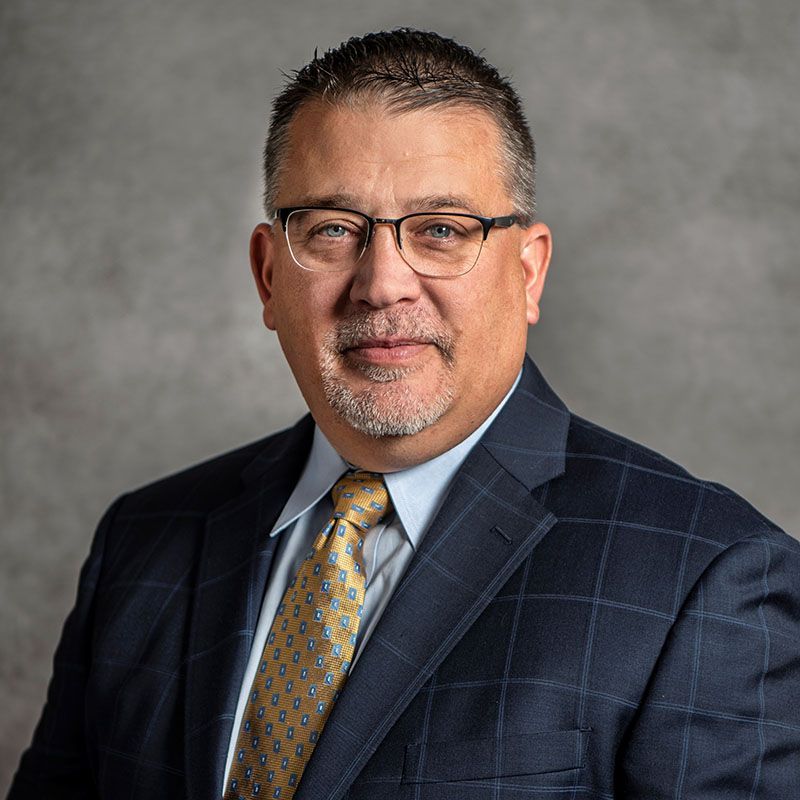 A man in a suit and tie is wearing glasses and a beard.