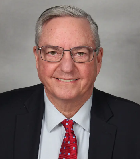 A man in a suit and tie is smiling for the camera