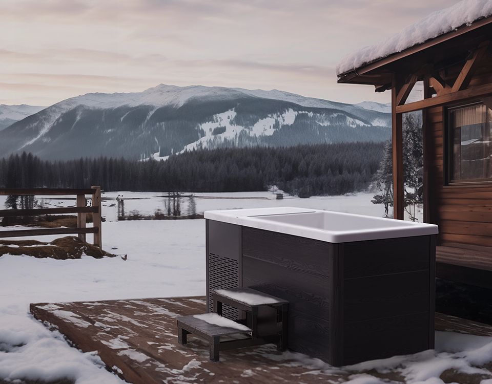 A hot tub is sitting outside of a cabin in the snow.