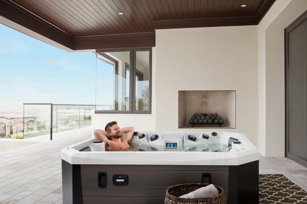 A man is sitting in a hot tub on a balcony.