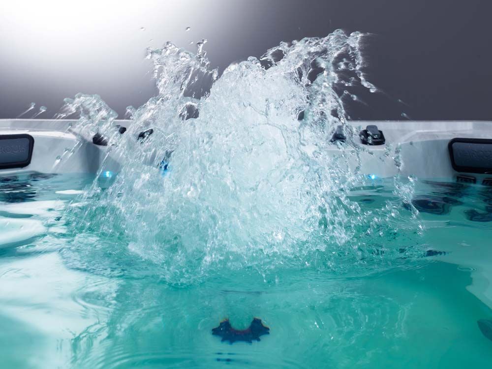 A close up of a hot tub with water splashing out of it.