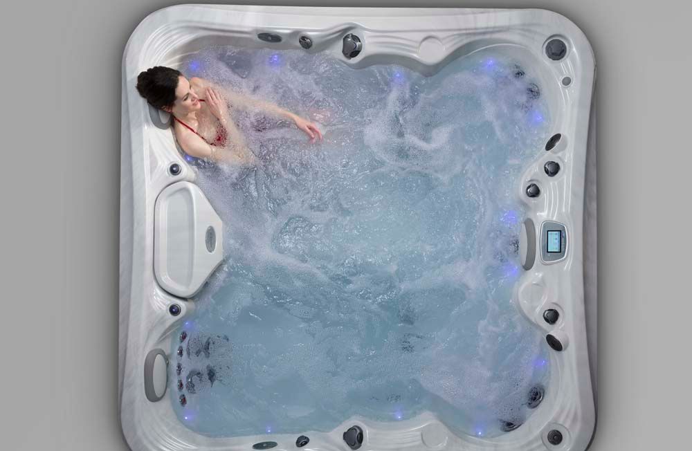 A woman is sitting in a hot tub on a gray background.