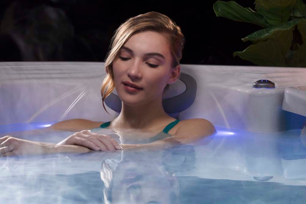 A woman is sitting in a hot tub with her eyes closed.