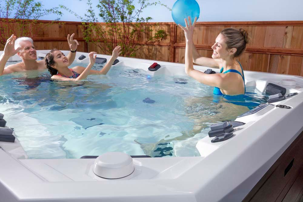 A group of people are playing with a ball in a hot tub.