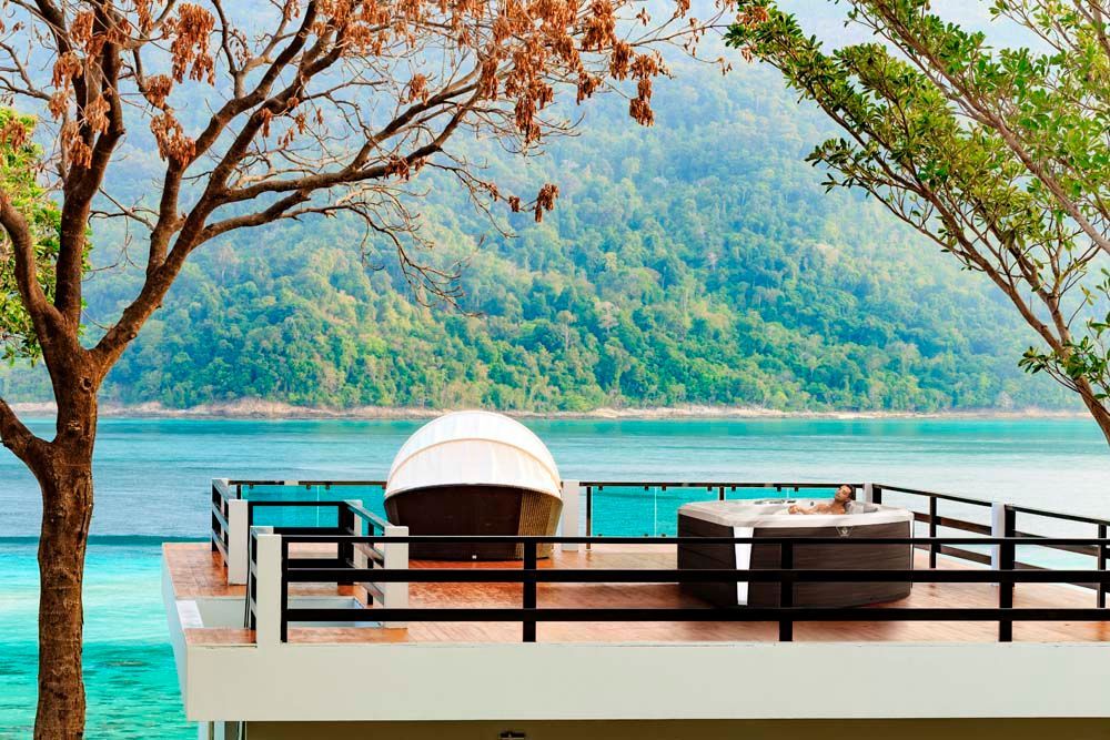 A balcony overlooking a swimming pool with a view of the ocean.