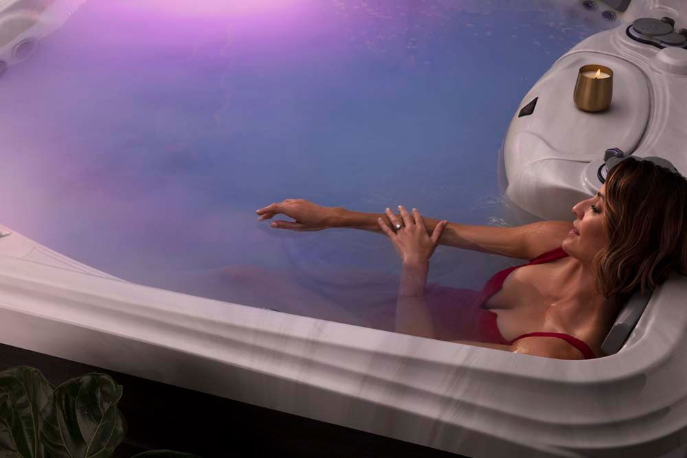 A woman is laying in a hot tub with a candle.