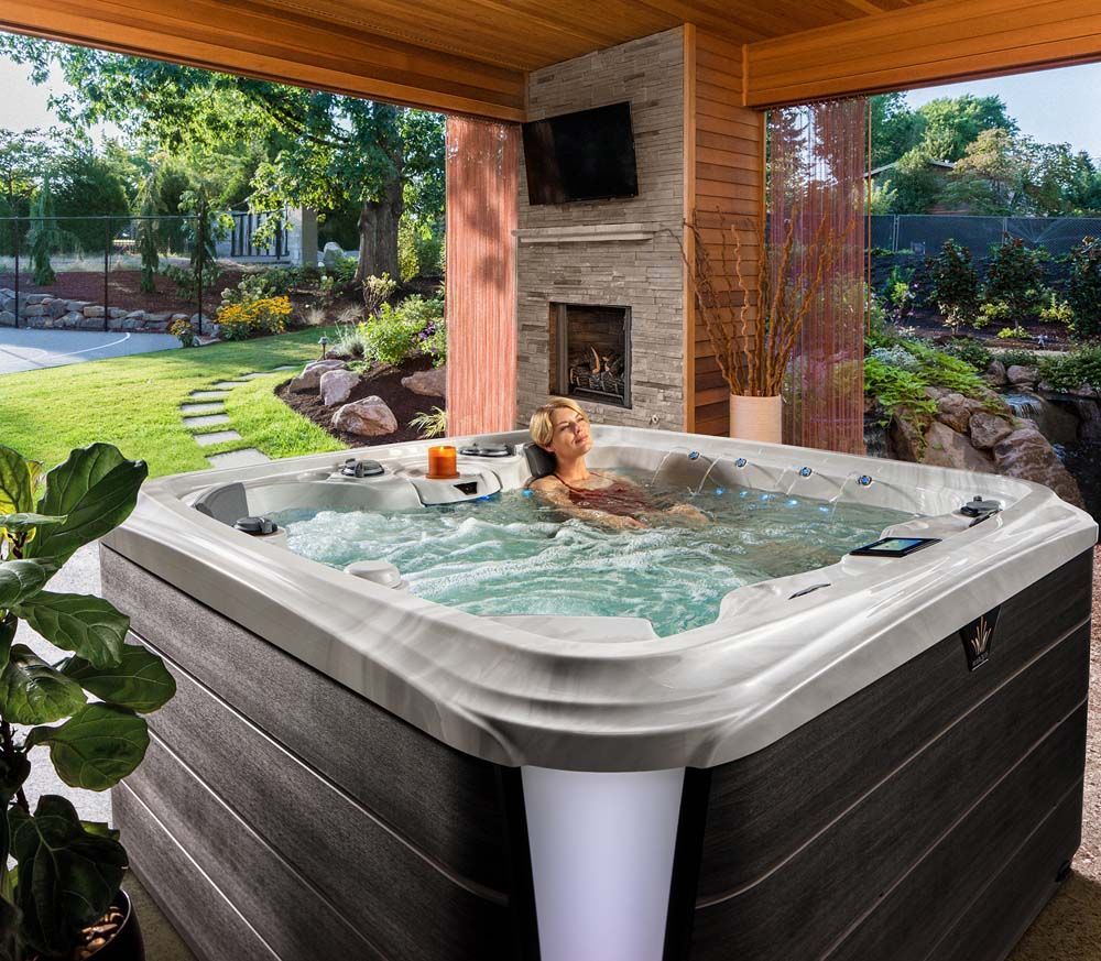 A woman is sitting in a hot tub with a fireplace in the background