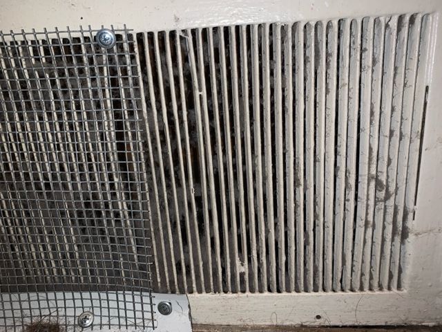 A dirty air vent with a metal mesh covering it