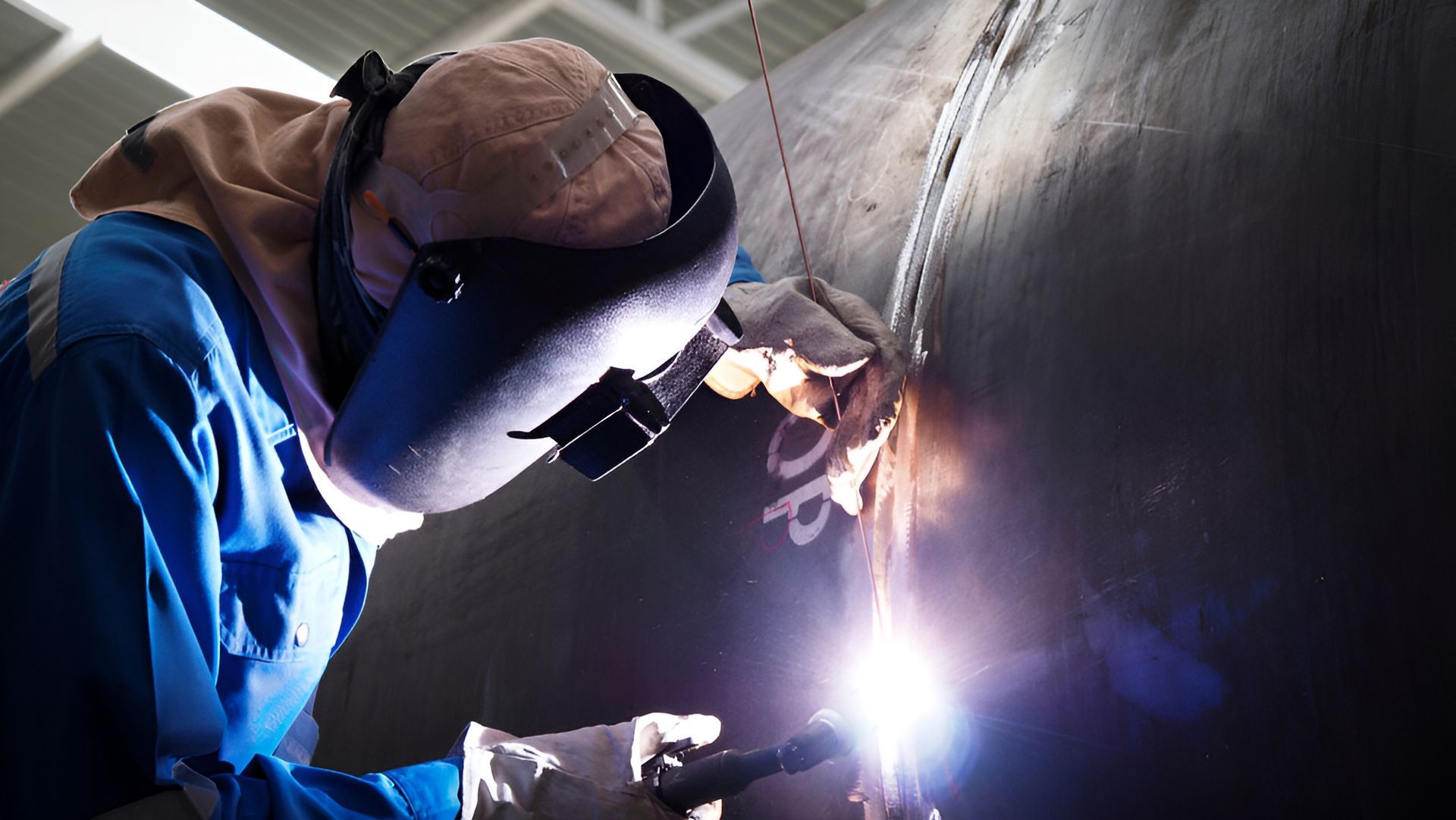Welder in Blue Uniform Welding Large Metal Pipe — LM Engineering in Georgetown, QLD