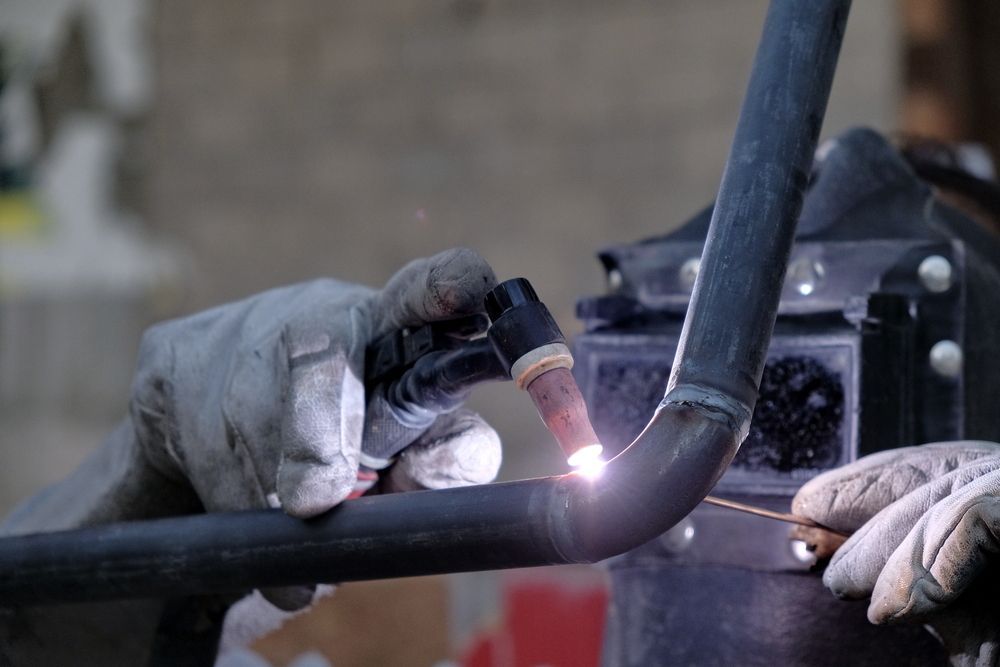 A Person is Welding a Metal Pipe With a Torch — LM Engineering In Mareeba, QLD
