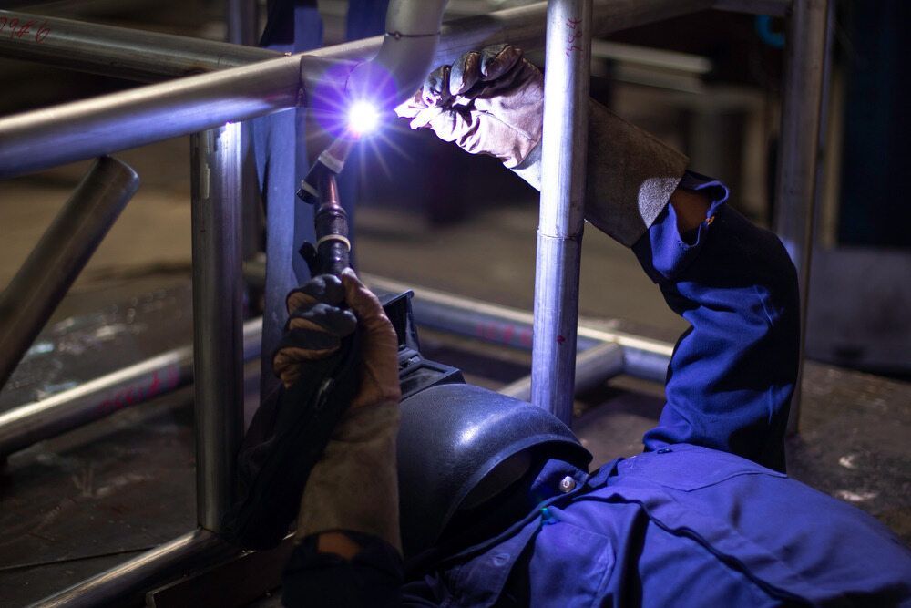 A Man is Welding a Metal Structure in a Factory — LM Engineering In Mareeba, QLD
