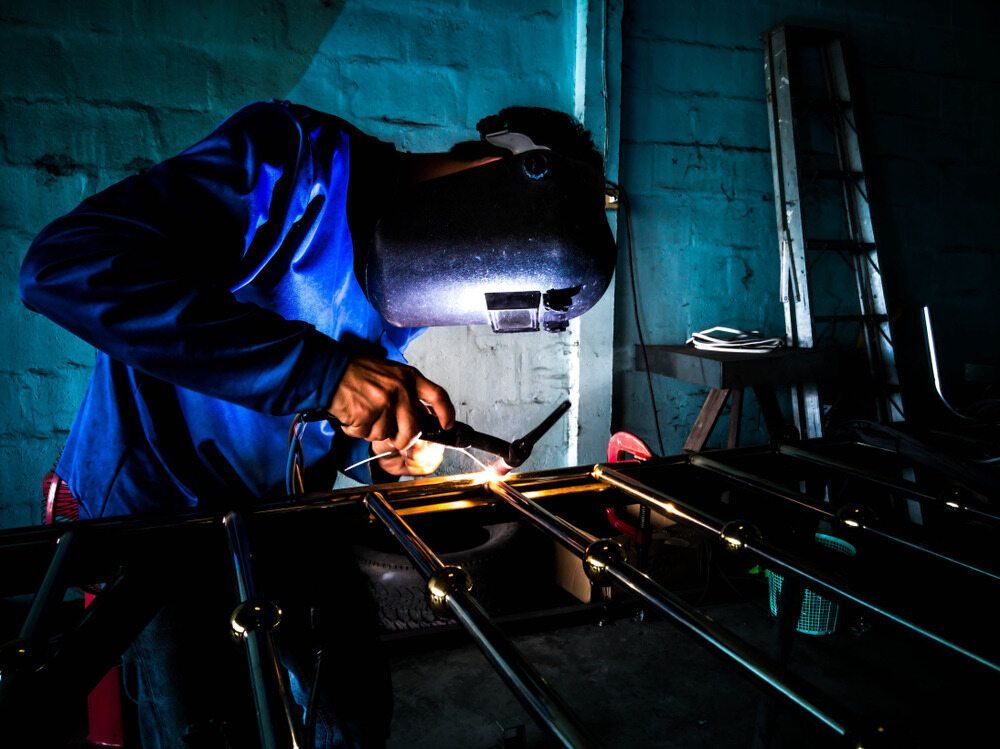 A Man is Welding a Piece of Metal in a Dark Room — LM Engineering In Mareeba, QLD