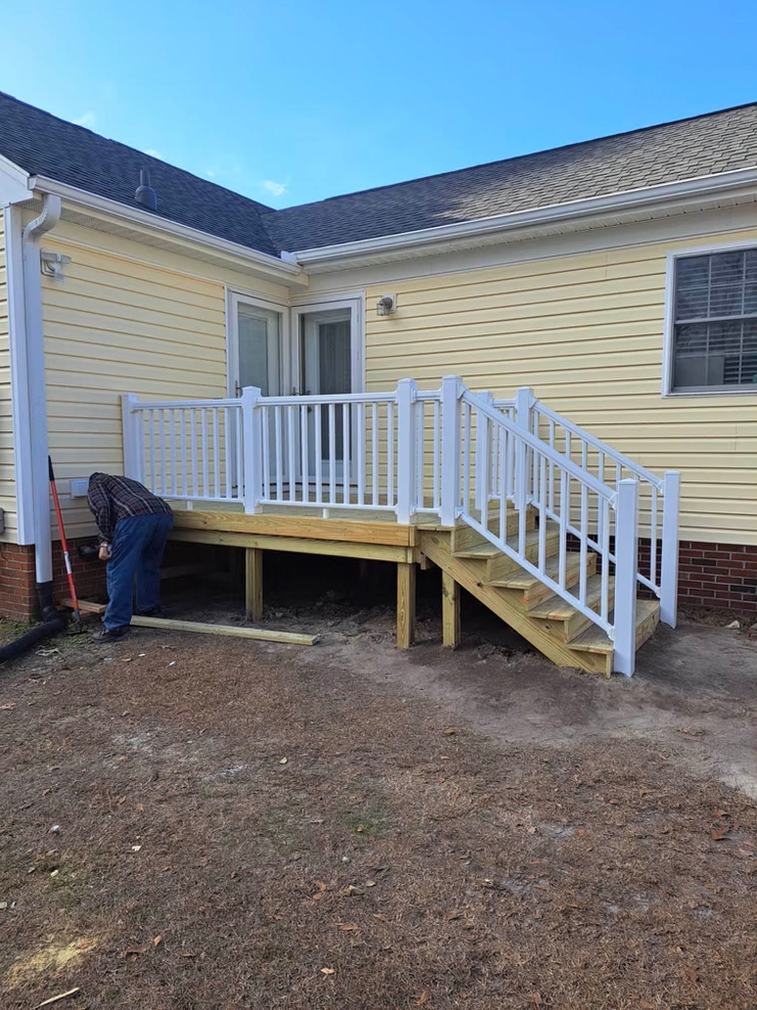 A man is working on a deck with stairs in front of a house.