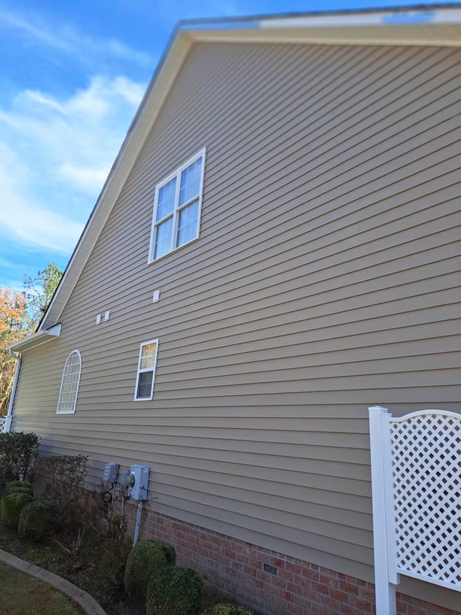 The side of a house with a lot of windows and a white lattice fence.