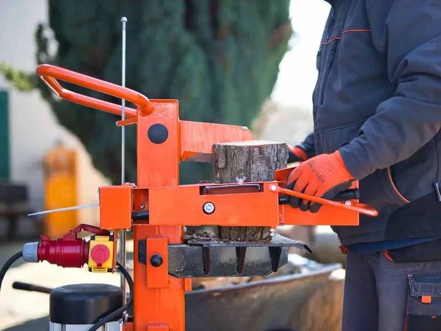 A man is using a log splitter to chop a log.
