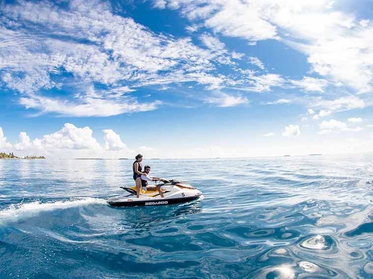 A man and a child are riding a jet ski in the ocean.