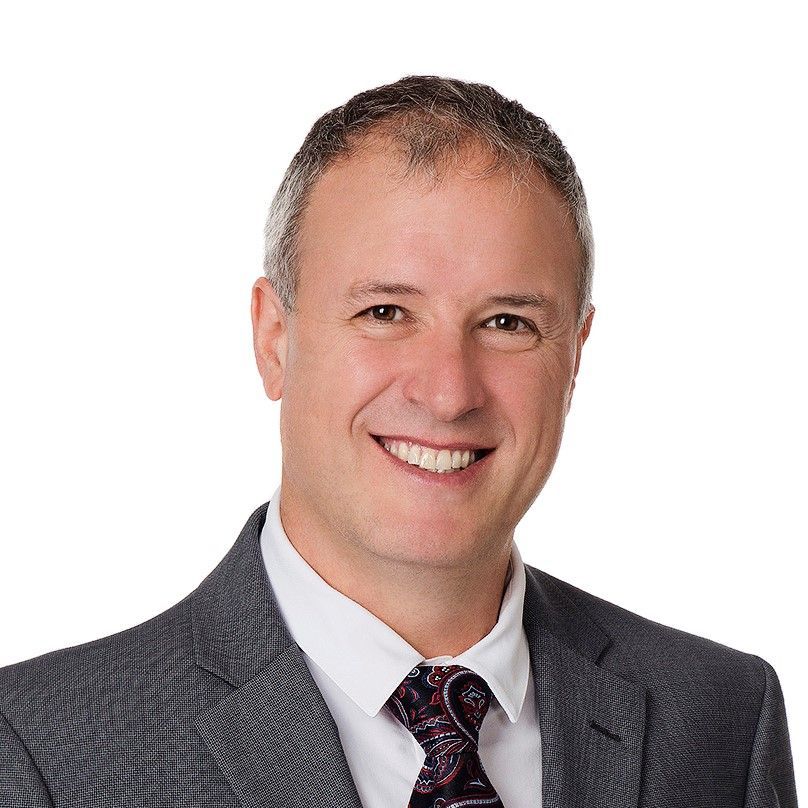 A man in a suit and tie is smiling for the camera