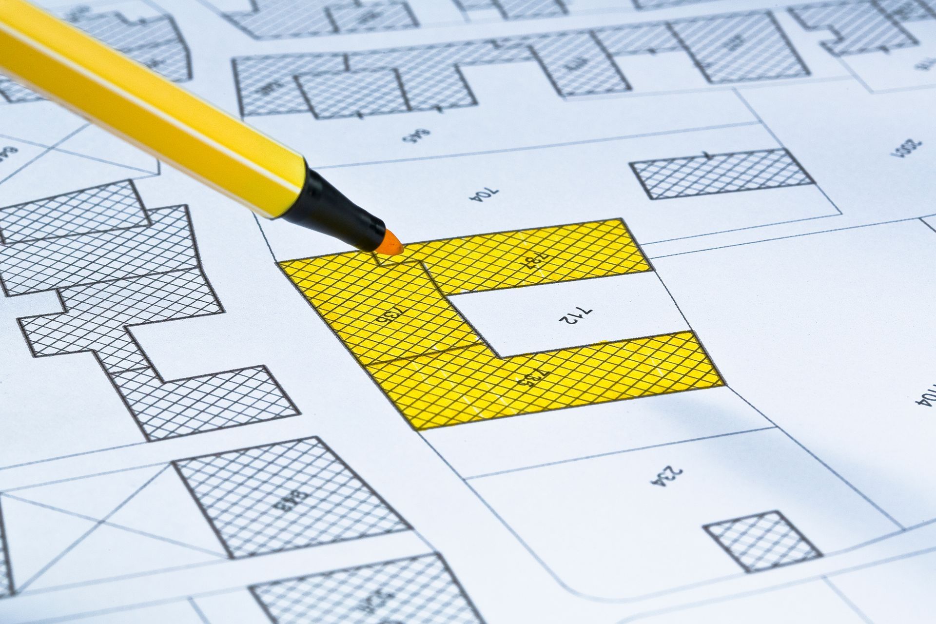 Un crayon jaune pointe un carré jaune sur une carte