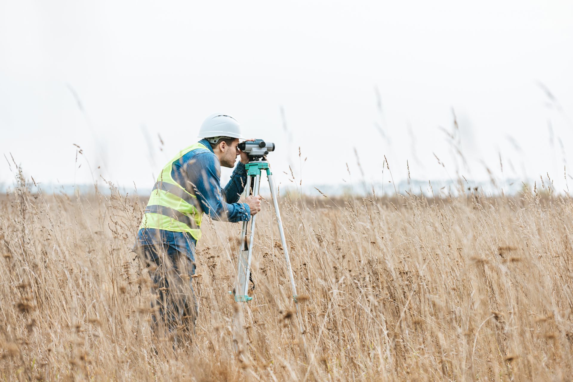 Un homme se tient dans un champ et regarde à travers un télescope.