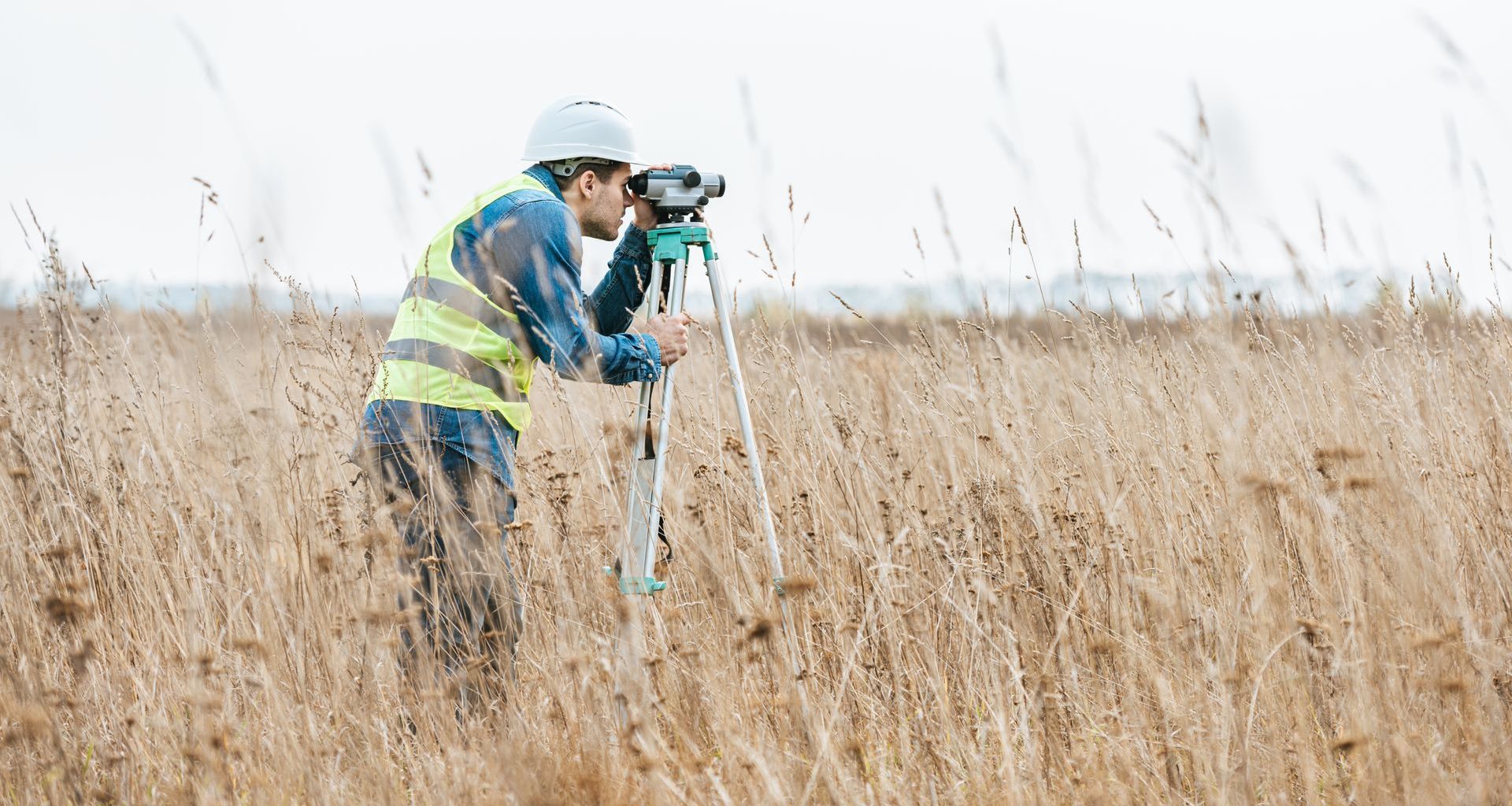Un homme se tient debout dans un champ et regarde à travers des jumelles.