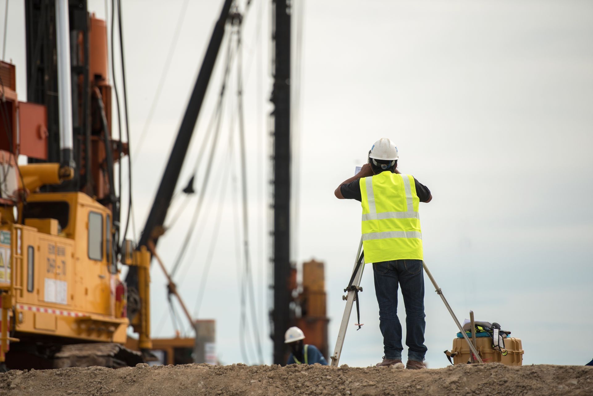 Un ouvrier du bâtiment se tient devant une grue sur un chantier de construction.