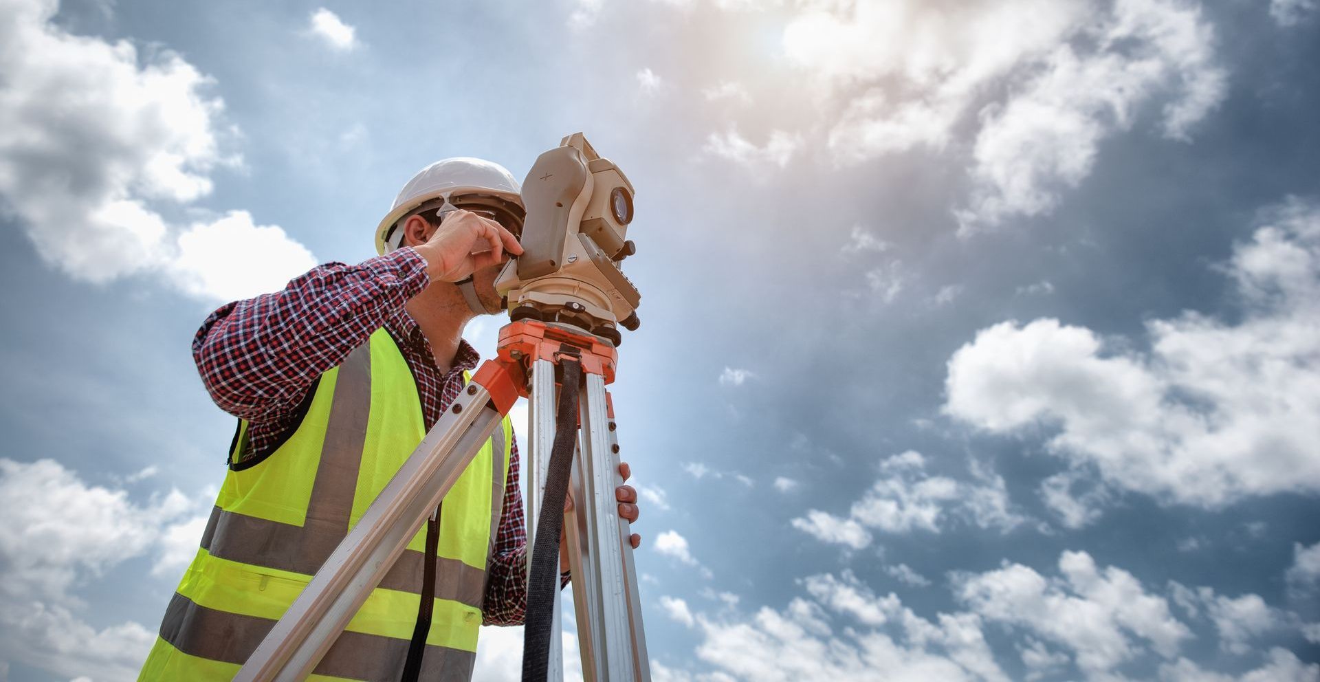 Un ouvrier du bâtiment utilise un théodolite sur un trépied.