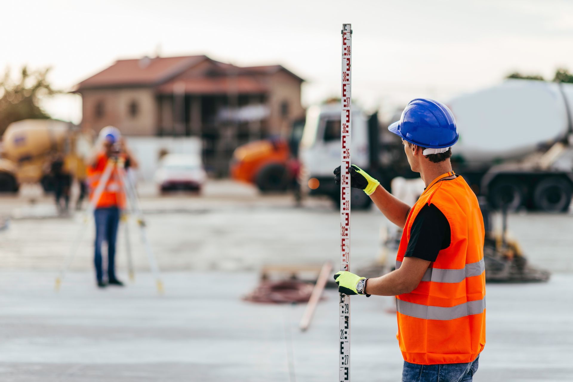 Un ouvrier du bâtiment mesure un poteau sur un chantier de construction.