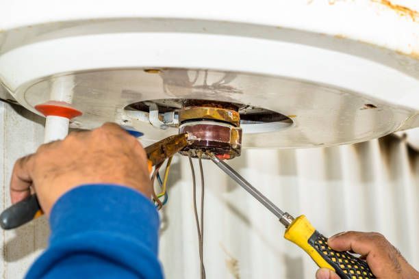 Person using a screwdriver to work on a water heater.