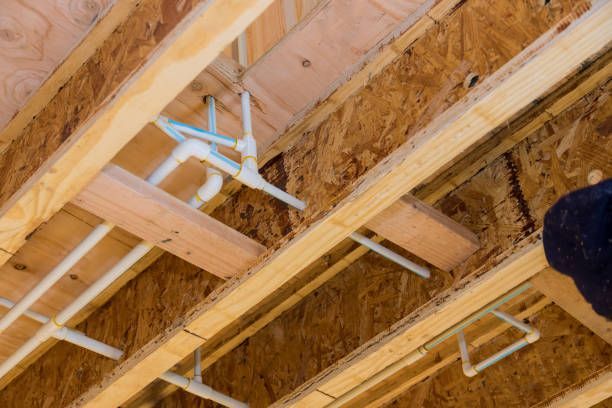Pipes and wooden beams in a ceiling, showing plumbing system in a wooden framed construction.
