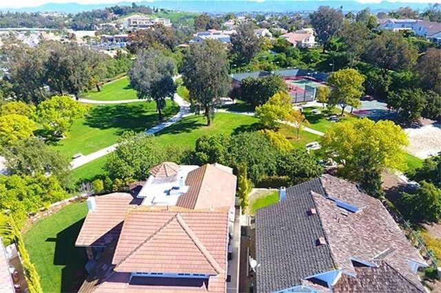 Aerial view of suburban homes, green parks, and trees on a sunny day