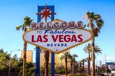 Welcome to Fabulous Las Vegas sign beneath a bright blue sky with palm trees