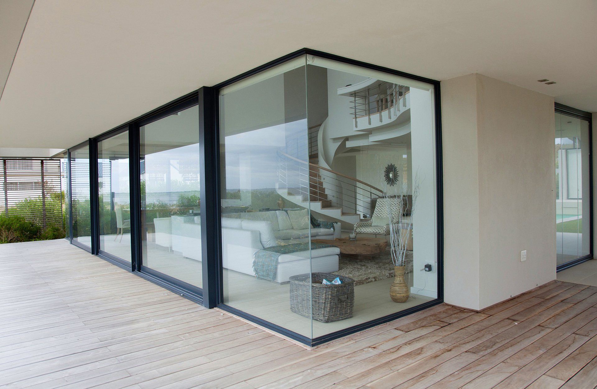 Modern house patio with floor-to-ceiling glass windows and a view into a bright living room