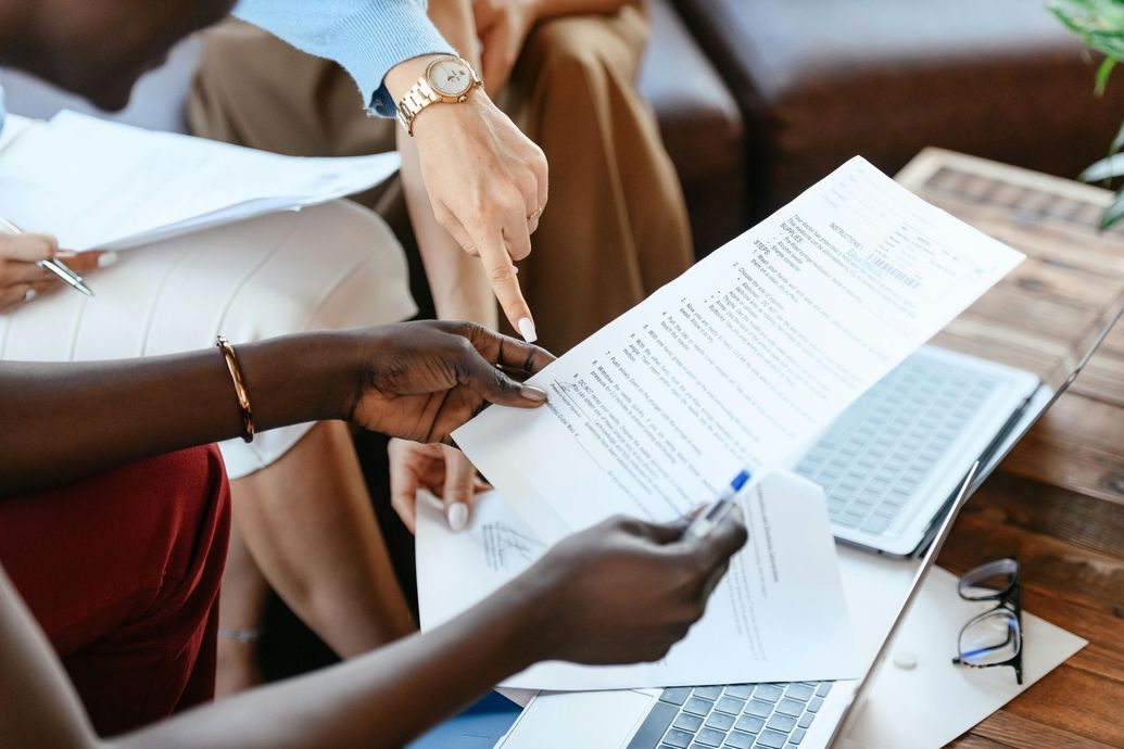 A group of people are sitting around a table looking at a piece of paper.