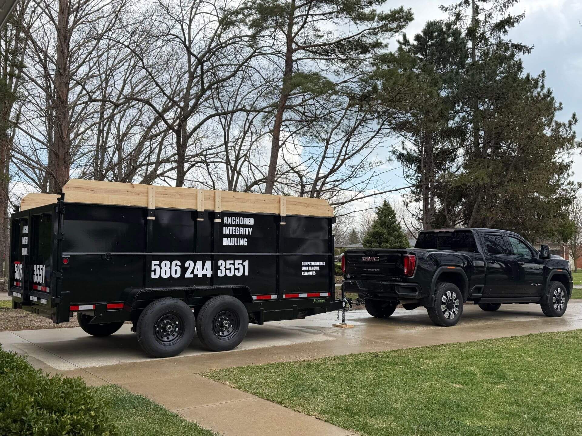 A pile of discarded wooden furniture scraps, planks, and debris strewn across an outdoor site.